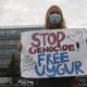 A woman holds a sign stating stop genocide. Organ harvesting, free uyghur. Uyghur, Uighur, Muslims, China, forced genocide.
