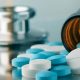 Blue and white pills are spilled near a stethoscope. assisted suicide, assisted death, euthanasia, euthanized