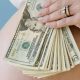 Woman holding cash over her pregnant belly. Surrogacy scandal.